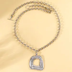 Primo piano dettagliato del ciondolo geometrico argento e della collana a catena spessa