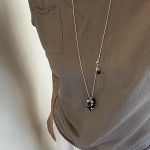 Detailed view of a long silver-tone tassel necklace with black and silver beads