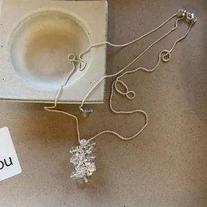 Detailed view of clear and pearl beaded cluster pendant on minimalist silver long chain