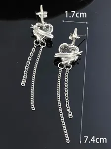 Detailed close-up view of long silver tassel earrings with heart and cross motifs and rhinestones
