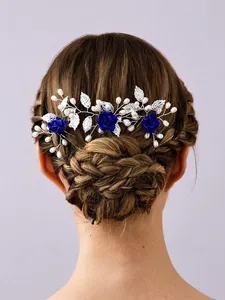 Detailed view of a bridal hair comb featuring blue roses and pearls on a braided bun