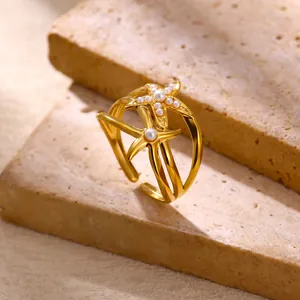 Dettaglio macro di un anello dorato a stella marina con perle su sfondo di pietra