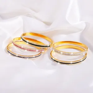 Elegante goldene Edelstahlarmreifen mit buntem Zirkonia-Inlay auf weißer Seide