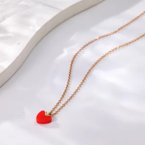 Detail view of a dainty gold necklace featuring a polished red heart pendant design.