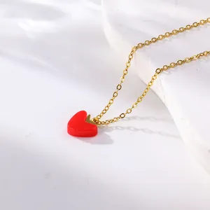 Close-up detail of a delicate gold titanium steel necklace featuring a red heart pendant