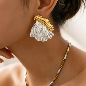 Close-up detail of exaggerated two-tone pleated stainless steel earring worn on the ear