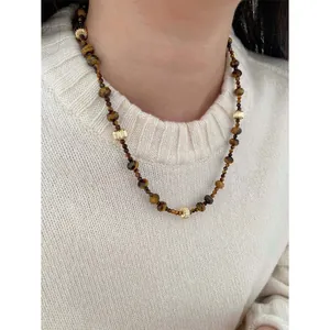 Collier vintage perles d'oeil de tigre et accents dorés porté sur un pull blanc chic