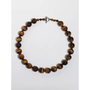 Vue détaillée du collier en œil de tigre naturel avec fermoir à bascule en T argenté.