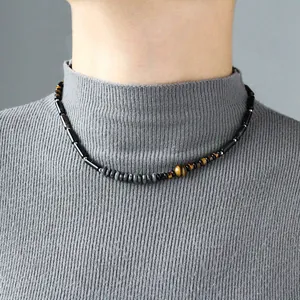Détail d'un collier vintage en perles d'oeil de tigre porté avec un pull gris