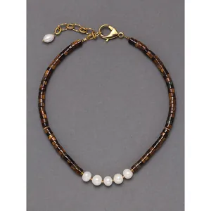 Gros plan d'un collier vintage en œil de tigre avec perles blanches et fermoir doré