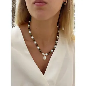 Gros plan d'un collier vintage en œil de tigre et perles porté par un mannequin.
