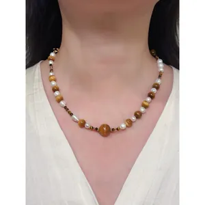 Vue rapprochée d'un élégant collier vintage en œil de tigre et perles sur le cou d'un modèle