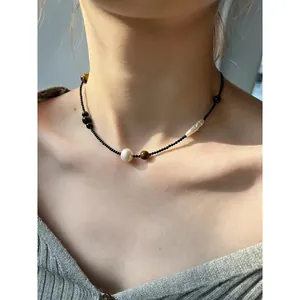 Vue détaillée d'un collier rétro en perles d'œil de tigre et perles blanches sur cou