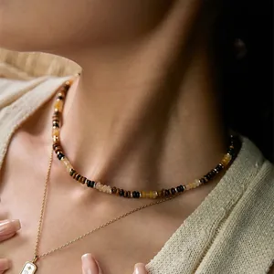 Gros plan d'un collier en perles d'œil de tigre rétro porté pour un look élégant et chic