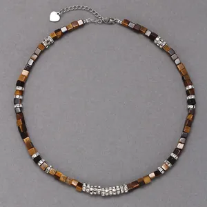 Détail de perles cubes en œil de tigre et d'entretoises en cristal sur un collier en acier.