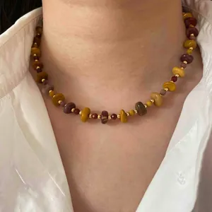 Gros plan d'un collier rétro en perles d'œil de tigre sur une chemise blanche