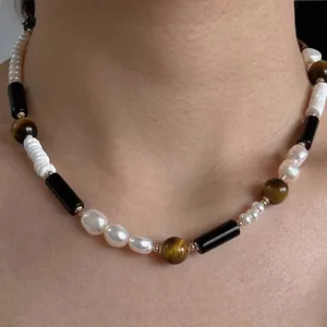 Gros plan d'un collier vintage en œil de tigre et perles sur un mannequin.