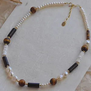 Gros plan d'un collier de perles vintage avec œil de tigre et chaîne plaquée or