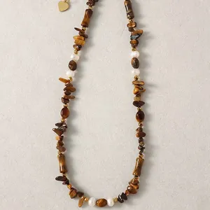 Gros plan d'un collier vintage en œil de tigre et perles avec pendentif cœur doré