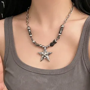Detailed view of a silver star pendant necklace with punk metal beads on a model.