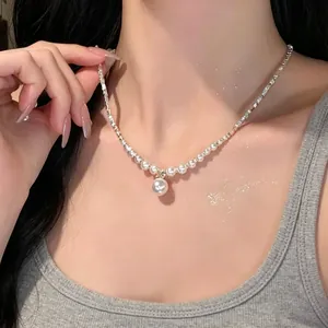 Close-up of elegant pearl necklace with silver chain on model's neck.