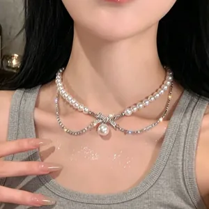 Detailed view of an elegant layered pearl necklace with bow-knot pendant on neck