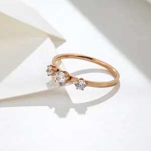 Macro-detail van een titaniumstalen ring met drie stenen en een roségouden afwerking.