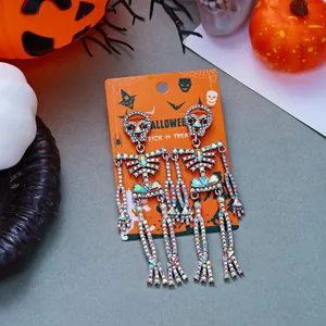 Vista dettagliata di orecchini a forma di scheletro di Halloween con strass su carta arancione.