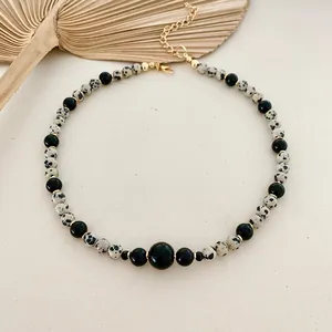Detailed shot of a dalmatian jasper and black bead necklace with gold clasp