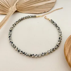 Close-up of Dalmatian jasper spotted bead necklace with golden extender chain.