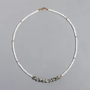 Detail of white tube shell beads and dalmatian jasper necklace on gray background