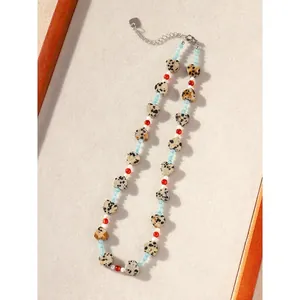 Detail view of a heart-shaped Dalmatian jasper beaded necklace on a textured background