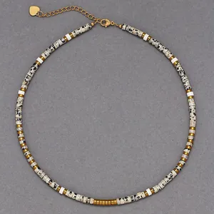 Detailed view of spotted stone bead necklace with gold spacers and heart charm