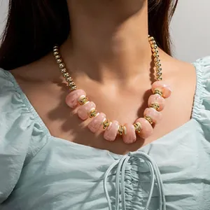 Collier rétro bohème avec perles en résine rose marbré et spacers dorés sur modèle