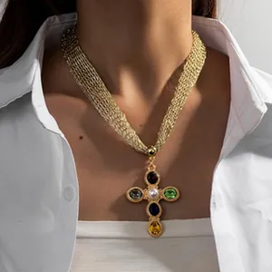 Gros plan d'un collier croix doré vintage avec pierres multicolores sur un modèle