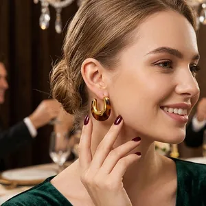 Primo piano di orecchini a goccia in tartaruga stile Maillard su una modella sorridente