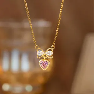 Elegante goldene Halskette mit rosa Herzanhänger und glitzerndem Schleifendetail