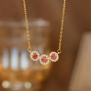 Elegante Goldhalskette mit drei roten Edelsteinen im Halo-Design