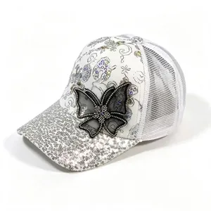 Detail shot of a stylish white baseball cap with silver sequins and a mesh butterfly.