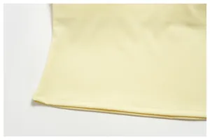 Close-up detail of pale yellow yoga tank top hemline with neat double stitching.
