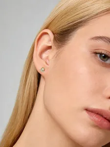 Primo piano di un orecchino a perno in argento sterling con opale indossato dal modello