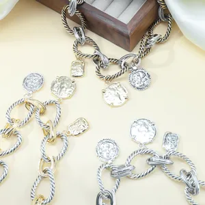 Detail view of two-tone twisted chain necklaces with vintage coin pendants and silk backdrop.