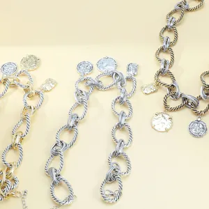 Detail view of chunky silver and gold twist chain necklaces with embossed coin pendants