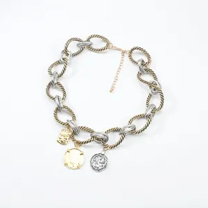 Close-up detail of a chunky two-tone twisted chain necklace featuring vintage coin pendants