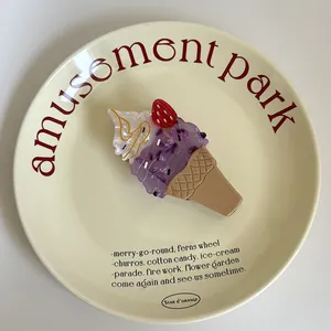 Gros plan d'une jolie pince à cheveux en forme de cornet de glace violet sur une assiette