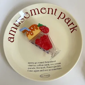 Zoom sur une pince à cheveux fantaisie en forme de sundae à la fraise sur une assiette.