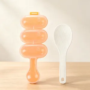 Close-up detail view of orange 3-cell DIY rice ball maker mold and small white rice paddle
