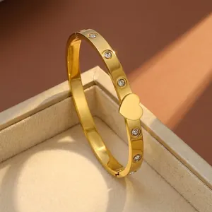 Detailed view of a gold stainless steel bangle featuring a heart charm and zircon stones