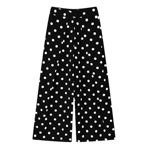 Detailed view of black and white polka dot wide leg pants with pleated waist.