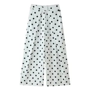 Detail of white wide-leg trousers featuring black polka dots and front pleats